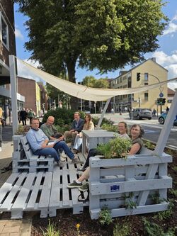 Palettenmöbel Sitzecke bei Sonnenschein in der Bahnhofstraße mit einigen Personen darauf sitzend