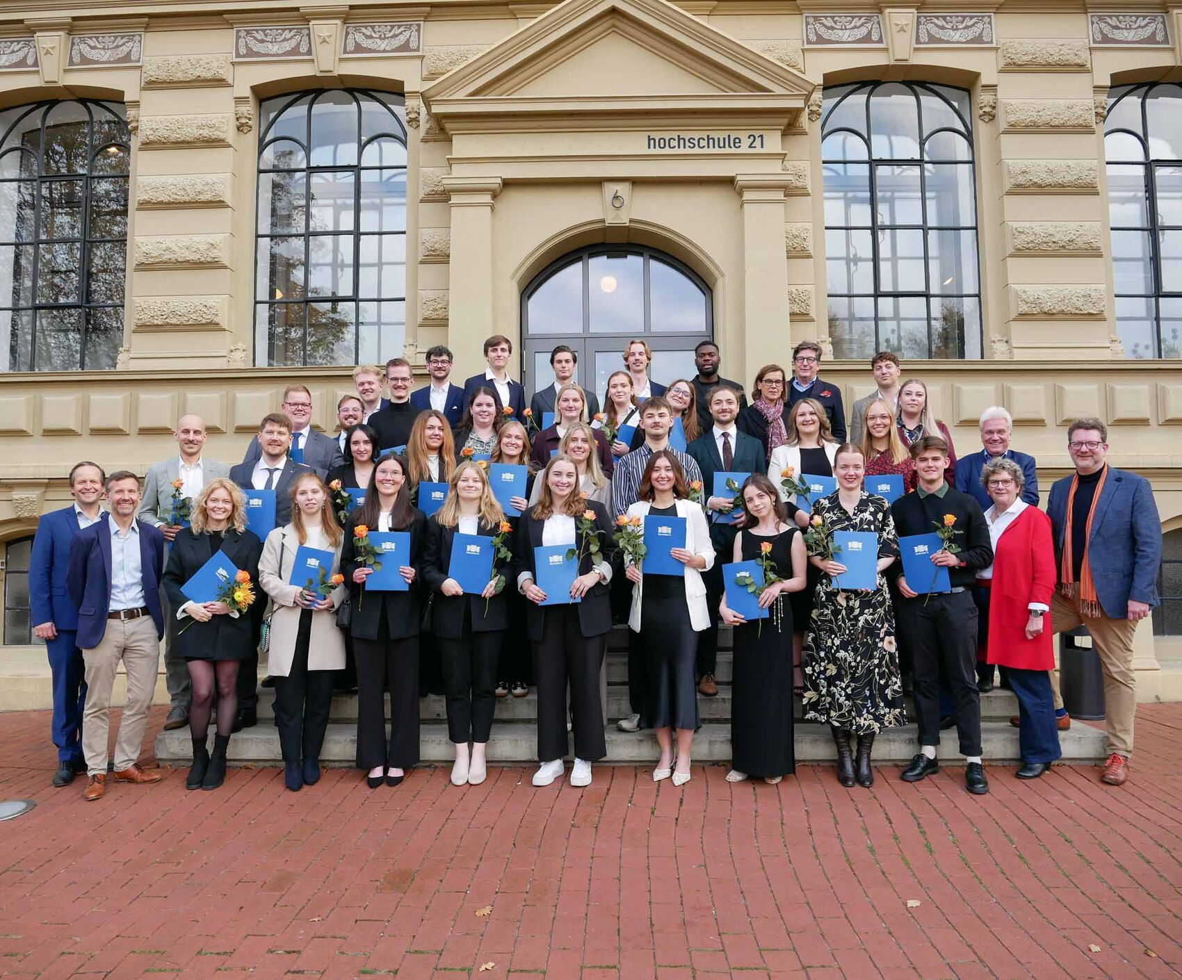 Gruppenfoto der Absolventinnen und Absolventen vor dem Hochschulgebäude.