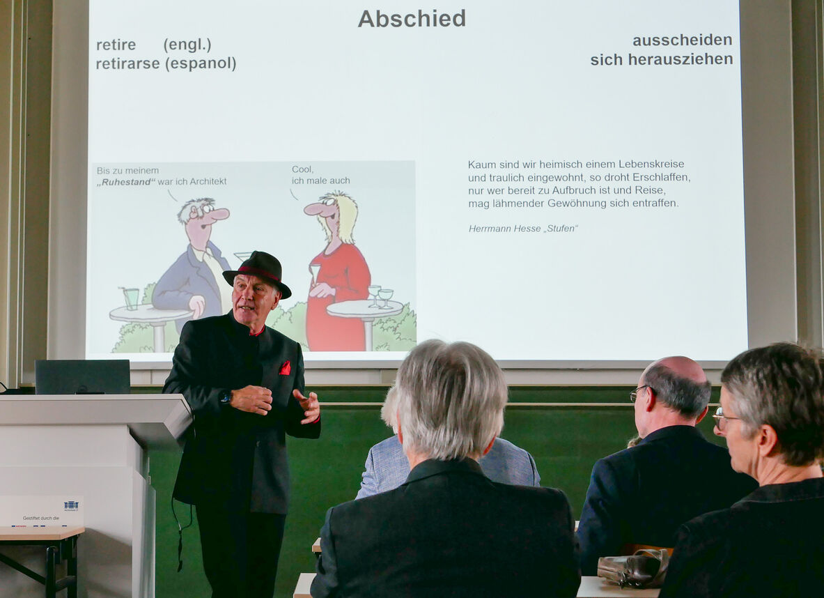 Jasper Herrmann steht vor seiner PowerPoint-Präsentation mit Bildern und Zitaten zum Thema Ruhestand