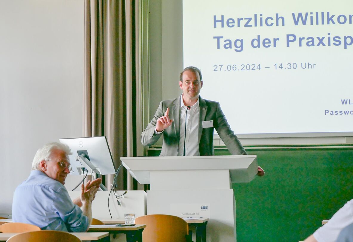 Prof. Dr.-Ing. Uwe Pfeiffer steht am Rednerpult, hinter ihm hängt die Leinwand mit der Präsentation darauf