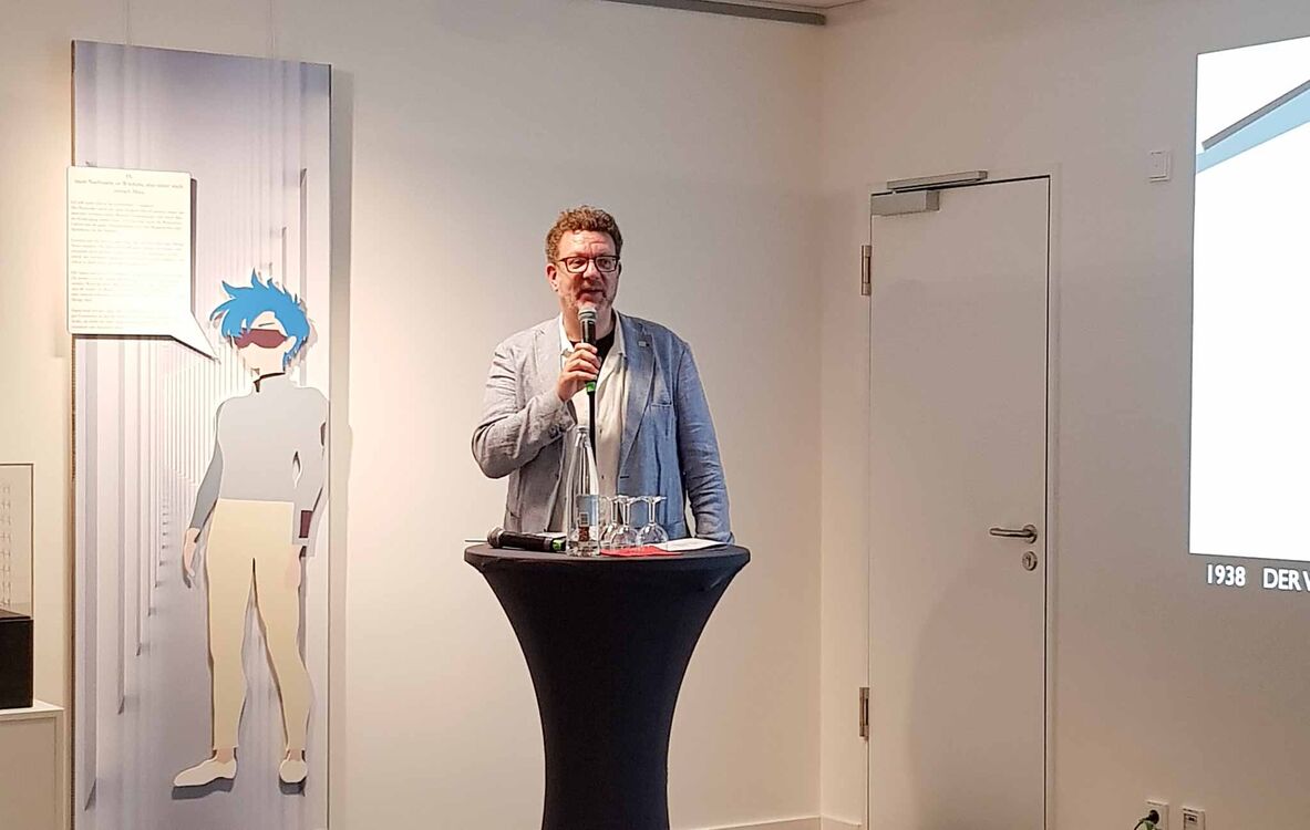 Prof. Dr.-Ing. Karsten Ley steht mit Mikrofon an einem Stehtisch.