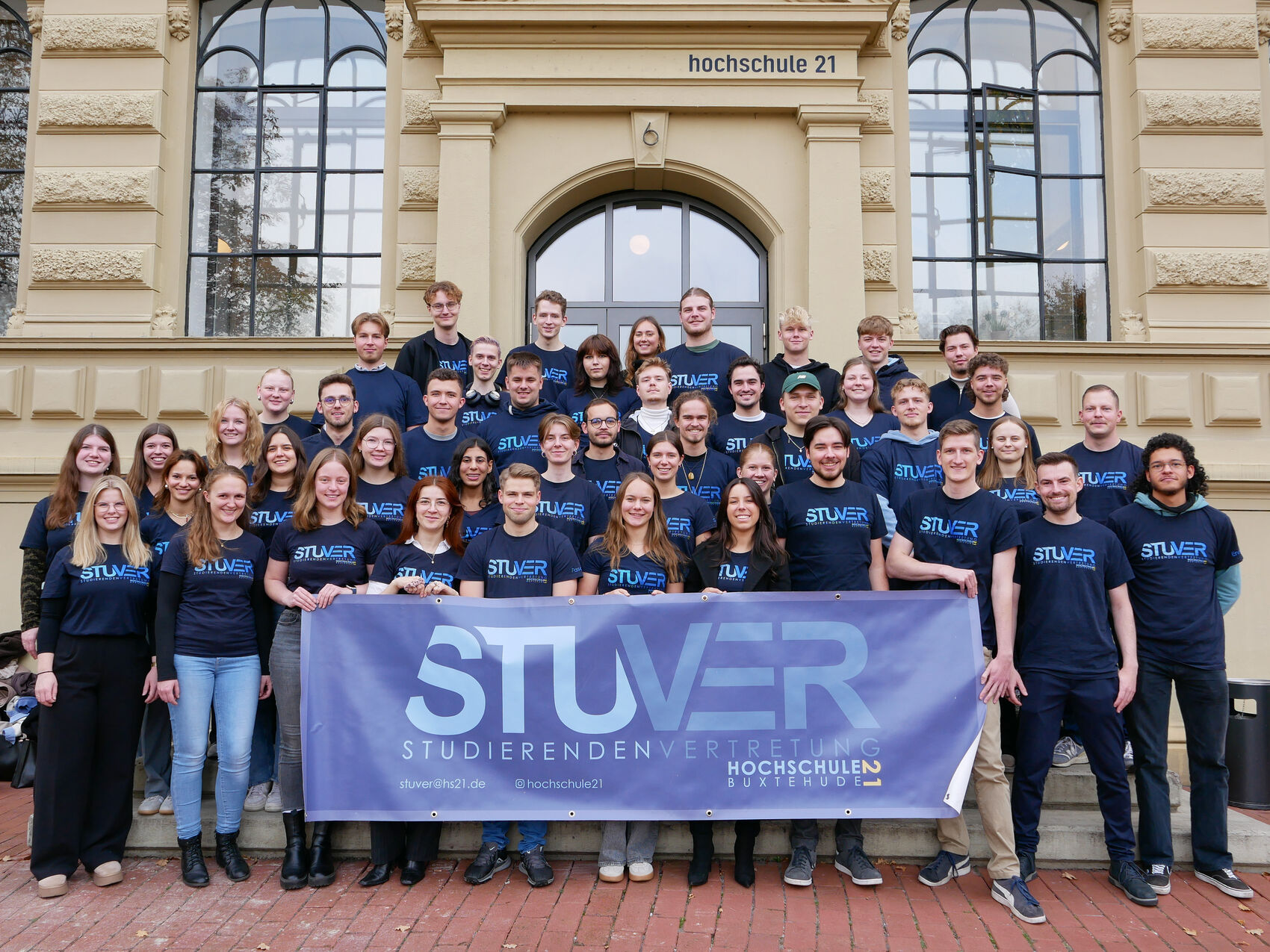Gruppenfoto der StuVer vor dem Hochschulgebäude mit StuVer-Banner.