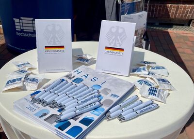 Auf einem Tisch liegen Infomaterialien zur hochschule 21 und Ausgaben des Grundgesetzes