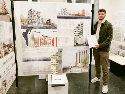 Konstantin Haase steht mit seiner Urkunde in der Hand vor seinem Entwurf