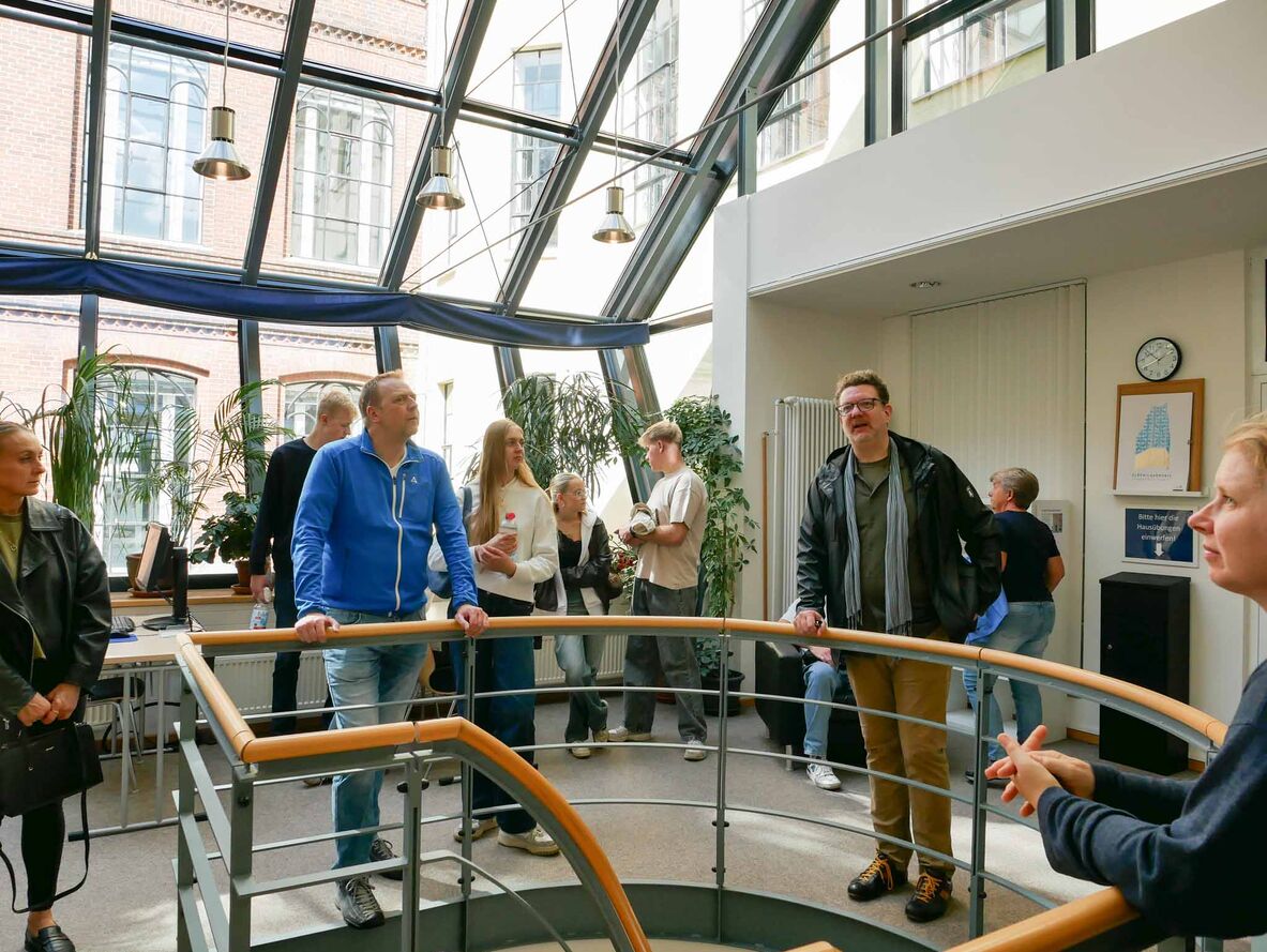 Prof. Dr.-Ing. Karsten Ley steht mit Teilnehmenden des Rundgangs in der Bibliothek.