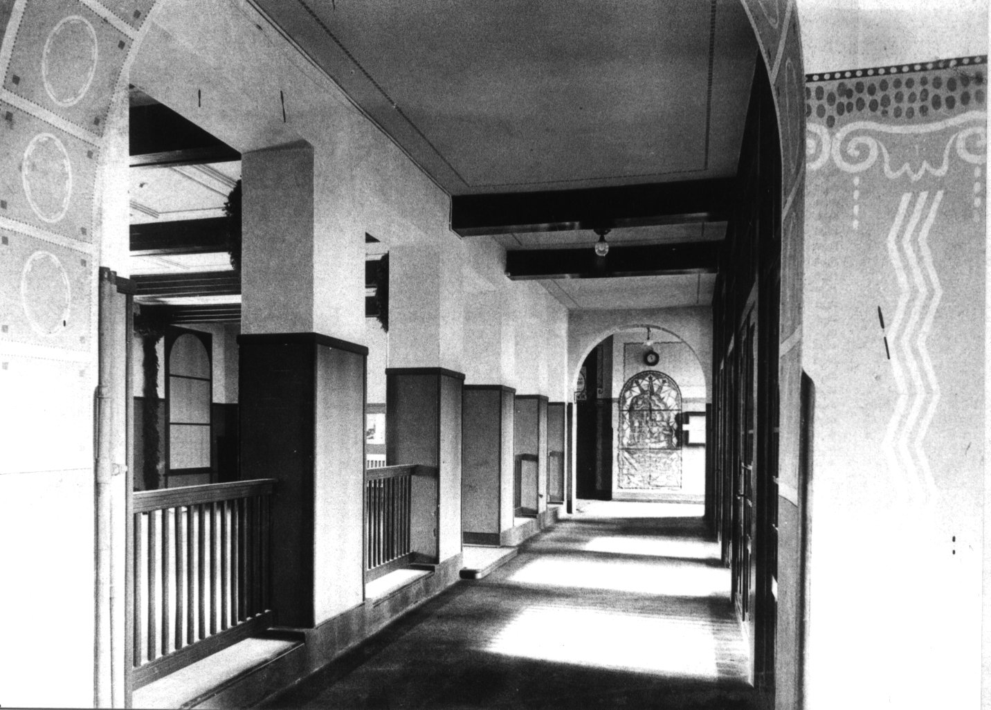 Schwarzweiß Fotografie des Eingangsbereichs der Hochschule mit dunkler halbhoher Wandvertäfelung und Malereien auf den Wänden